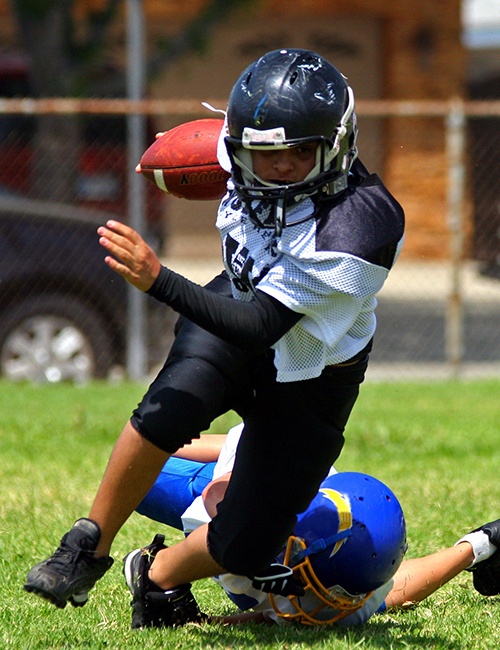 Child playing football with athletic mouthguard