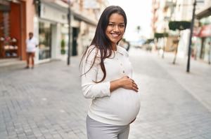 Pregnant woman smiling and walking down street